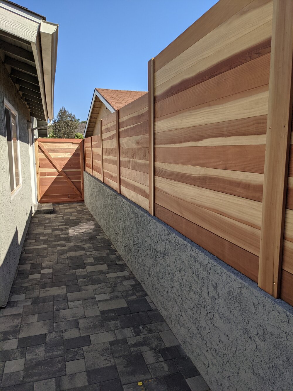 Wooden cedar fence with custom gate on block retaining wall.