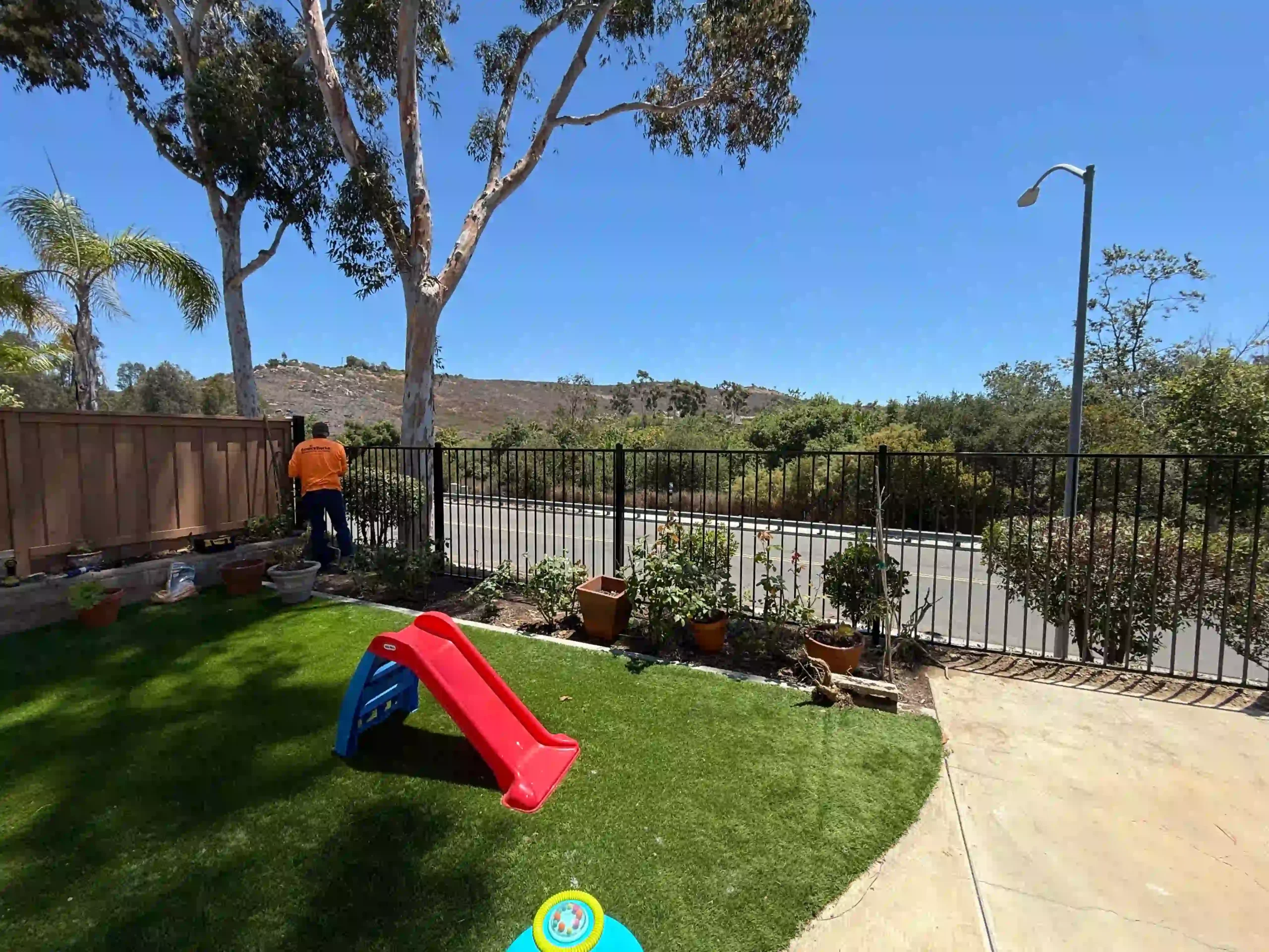 Worker doing final install of wrought iron fence in a san diego backyard