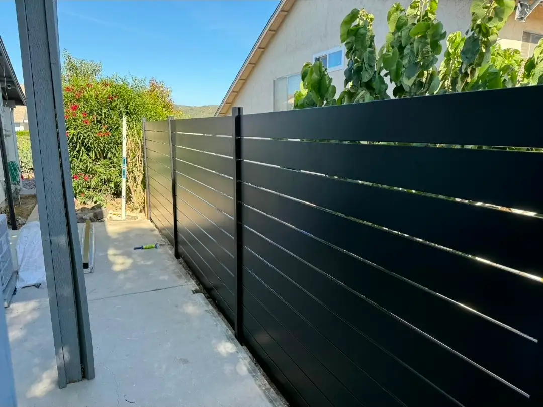 Modern black horizontal aluminum privacy fence installed along a residential side yard in San Diego County